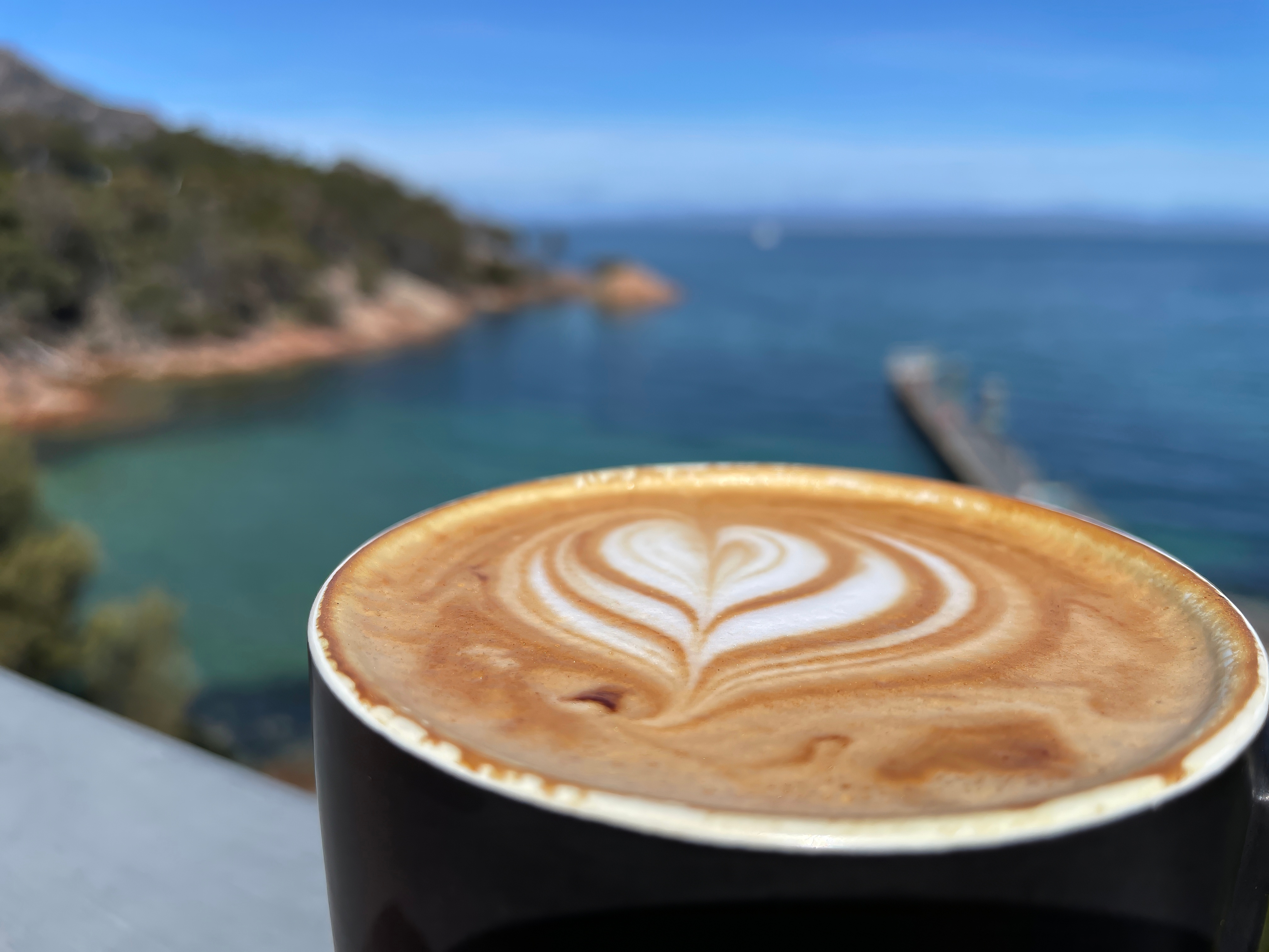 Selective focus view of a cup of hot Caffe latte with beautiful latte art, in beautiful ocean it is a coffee drink made with espresso and steamed milk.